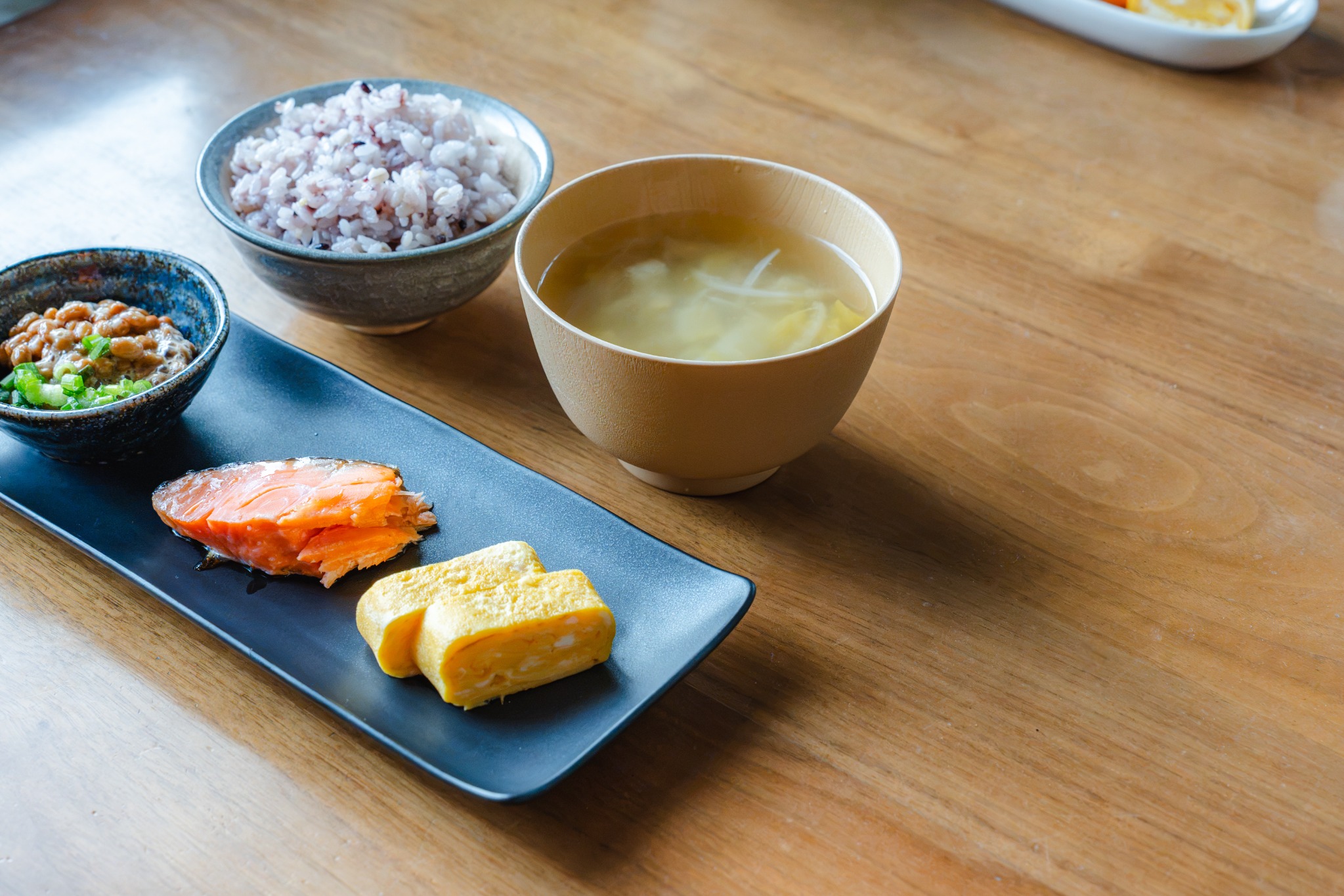 ご飯、味噌汁、焼き魚、卵焼きなどが並ぶ和食の食卓