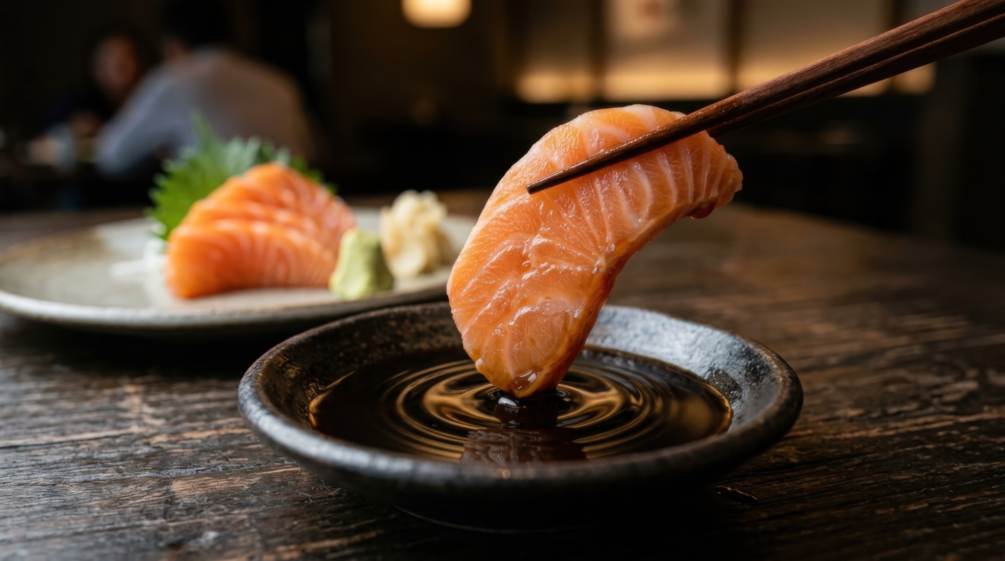 箸で持った刺身の端を醤油につける様子